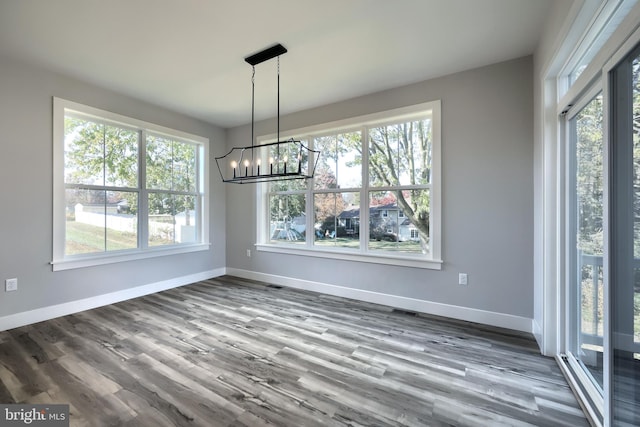 unfurnished dining area featuring a wealth of natural light, a chandelier, and hardwood / wood-style flooring