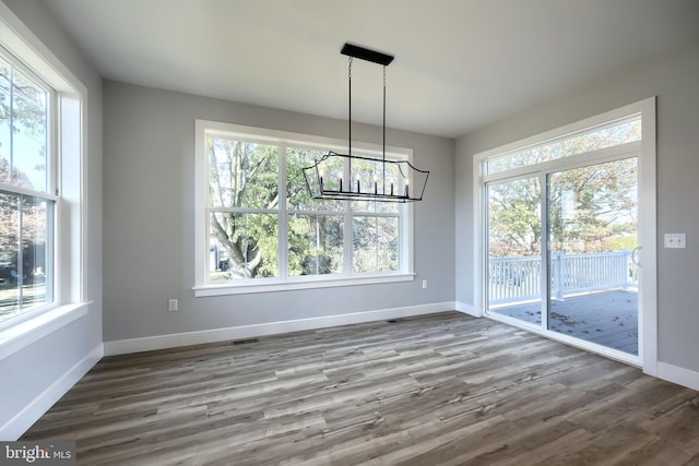 unfurnished dining area featuring hardwood / wood-style floors and an inviting chandelier