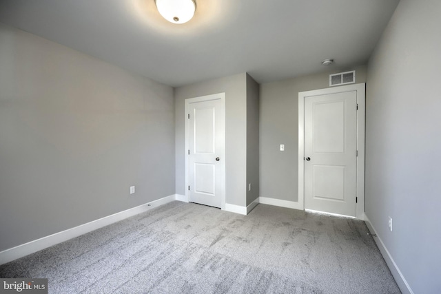 unfurnished bedroom featuring a closet and light colored carpet