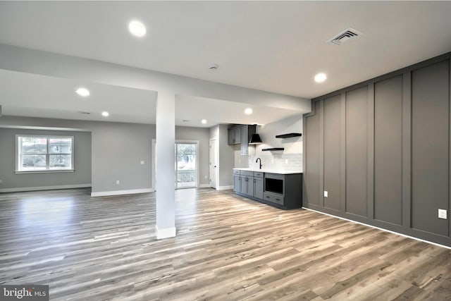 unfurnished living room with light hardwood / wood-style flooring, a healthy amount of sunlight, and sink