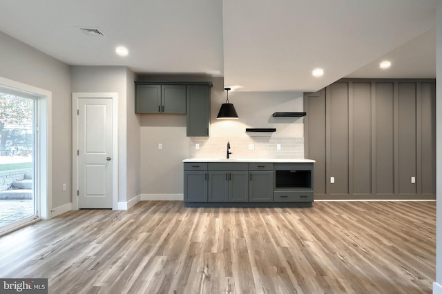 kitchen featuring tasteful backsplash, sink, pendant lighting, light hardwood / wood-style flooring, and gray cabinets