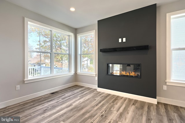 unfurnished living room featuring a fireplace, a wealth of natural light, and hardwood / wood-style floors