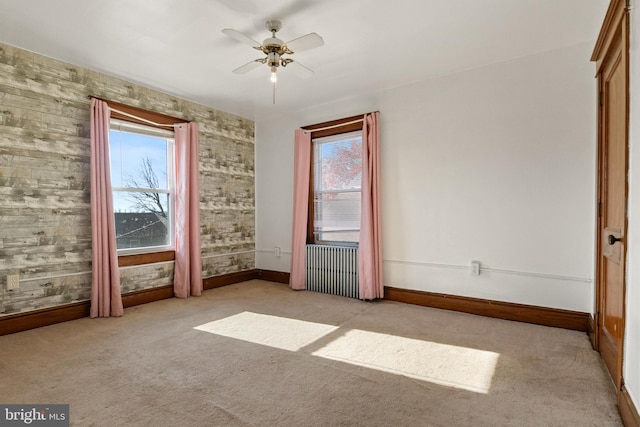 empty room with light carpet, radiator heating unit, and ceiling fan