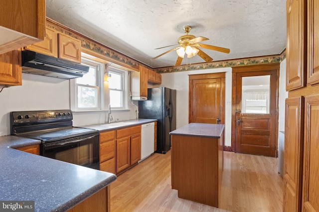 kitchen with black appliances, sink, ceiling fan, light wood-type flooring, and a kitchen island