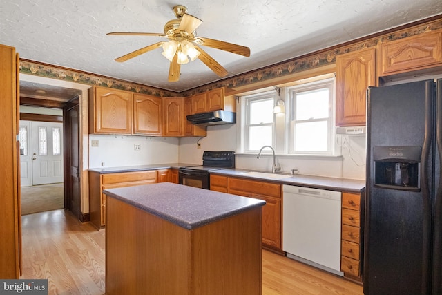 kitchen with black appliances, a center island, sink, and light hardwood / wood-style flooring