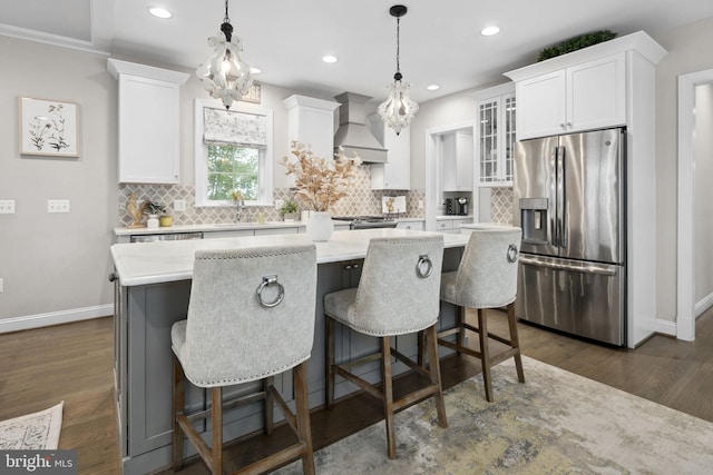 kitchen featuring appliances with stainless steel finishes, a center island, hanging light fixtures, and custom exhaust hood