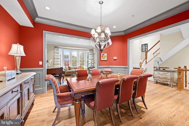 dining space with ornamental molding, a notable chandelier, and light wood-type flooring