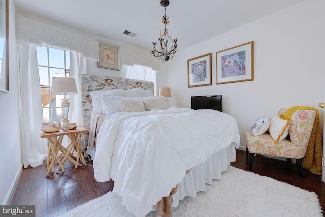 bedroom featuring wood finished floors, baseboards, and a chandelier