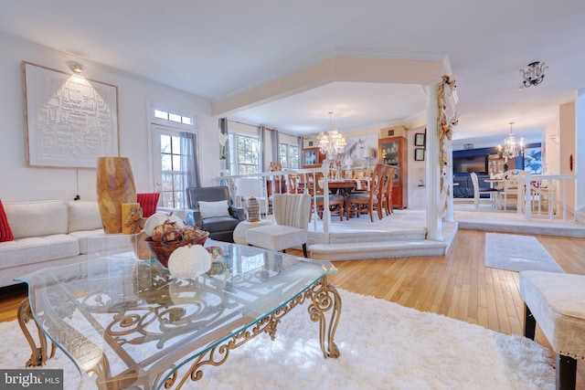 living room featuring a chandelier, wood-type flooring, and ornamental molding