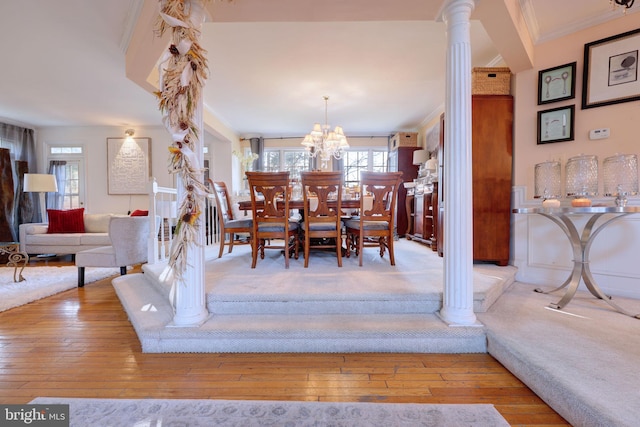 dining area featuring decorative columns, hardwood / wood-style floors, crown molding, and a chandelier