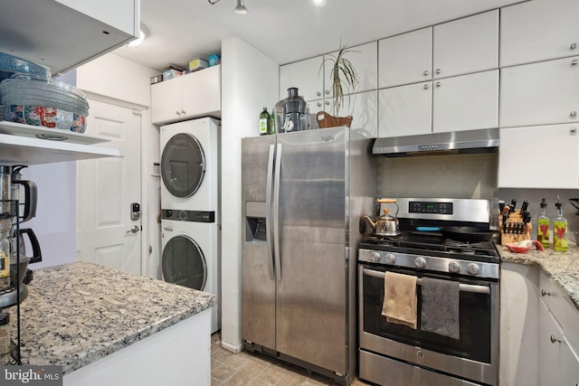 kitchen featuring white cabinetry, stacked washer and dryer, light stone counters, and appliances with stainless steel finishes