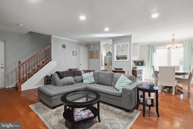 living room with wood-type flooring, ornamental molding, and a notable chandelier