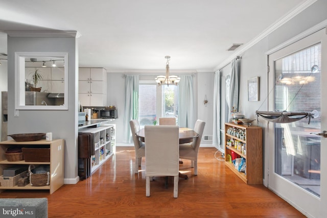 dining space with crown molding, a chandelier, and hardwood / wood-style flooring