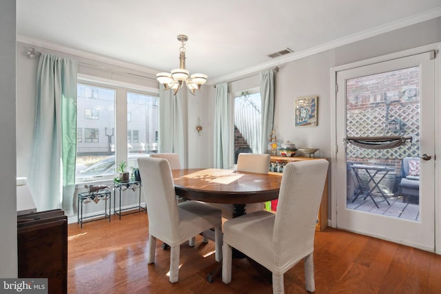 dining area with crown molding, a chandelier, and hardwood / wood-style flooring