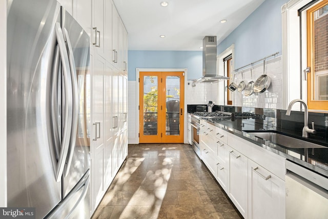 kitchen with white cabinetry, sink, wall chimney exhaust hood, french doors, and appliances with stainless steel finishes