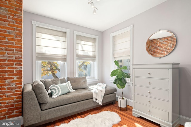 living area with brick wall and light wood-type flooring