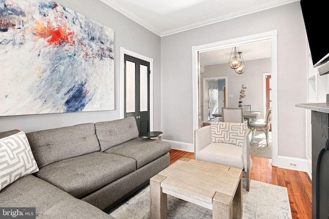 living room featuring hardwood / wood-style floors, ornamental molding, and an inviting chandelier