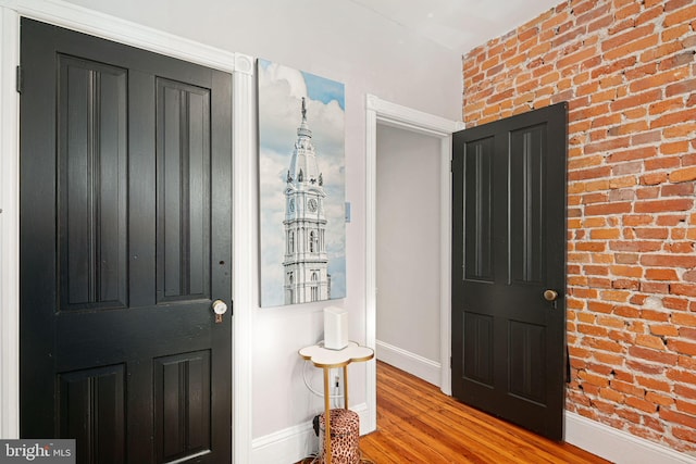 entrance foyer featuring brick wall and light wood-type flooring