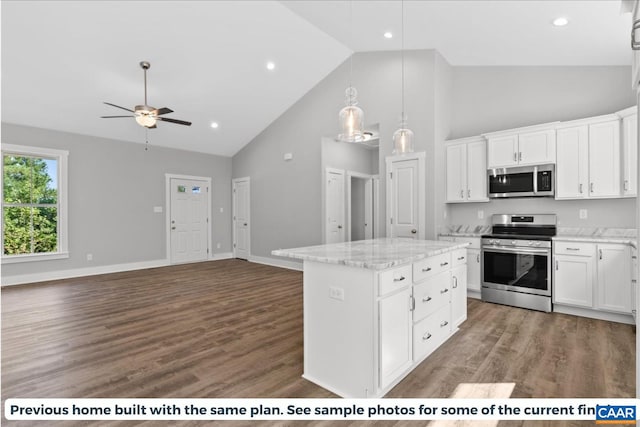 kitchen with high vaulted ceiling, stainless steel appliances, white cabinetry, and a kitchen island