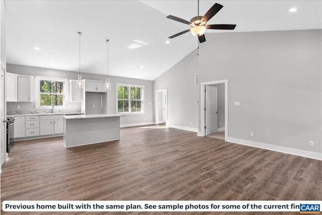 kitchen with white cabinetry, a center island, high vaulted ceiling, and a healthy amount of sunlight