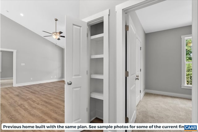 hall featuring light wood-type flooring, built in features, and vaulted ceiling