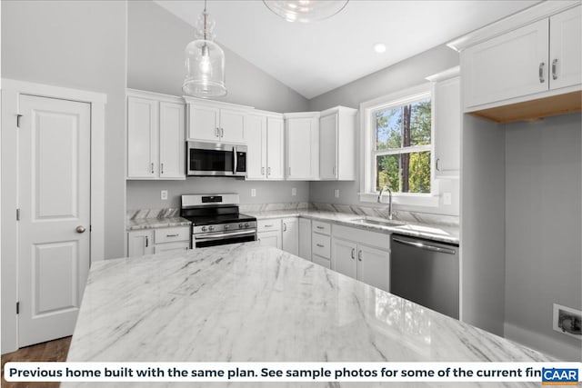 kitchen featuring stainless steel appliances, white cabinetry, lofted ceiling, and light stone counters