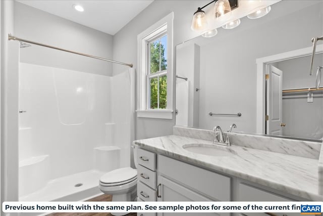 bathroom featuring walk in shower, vanity, and toilet