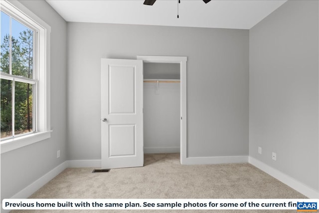 unfurnished bedroom with ceiling fan, a closet, and light colored carpet