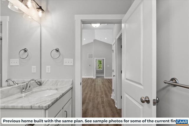 bathroom with vanity, wood-type flooring, and lofted ceiling