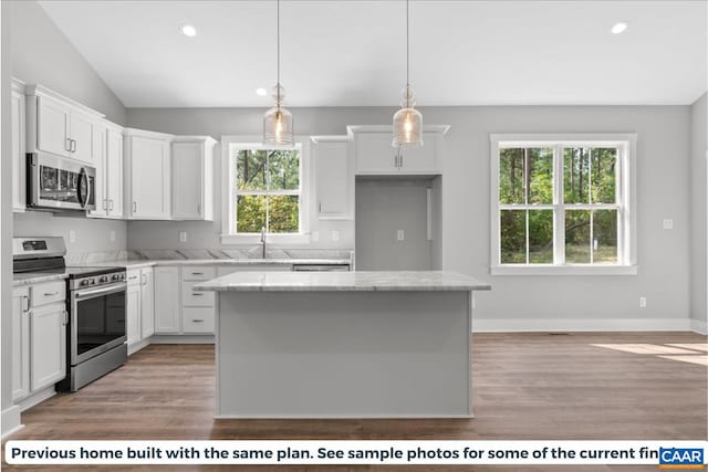 kitchen with a wealth of natural light, white cabinetry, a center island, and stainless steel appliances