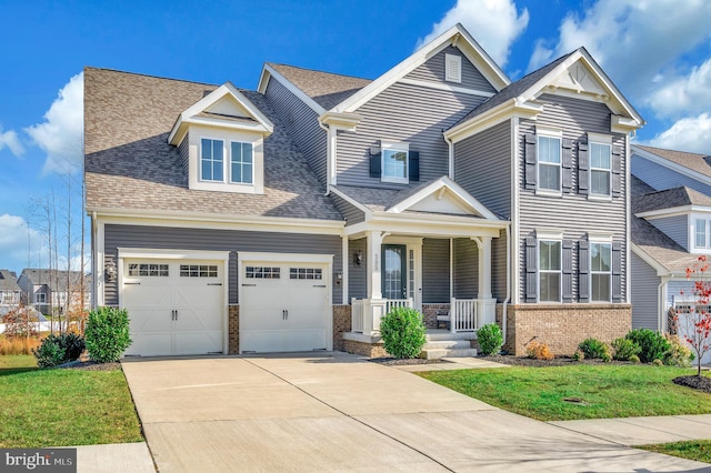 view of front of property featuring covered porch, a garage, and a front yard