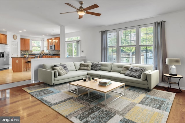 living room featuring light hardwood / wood-style floors and ceiling fan with notable chandelier