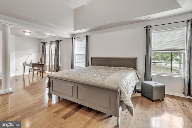 bedroom with ornate columns and light hardwood / wood-style flooring