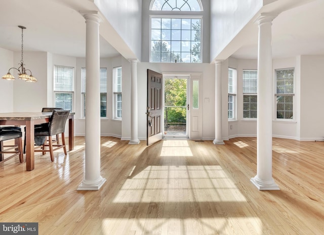 foyer featuring light hardwood / wood-style flooring, a towering ceiling, and a notable chandelier