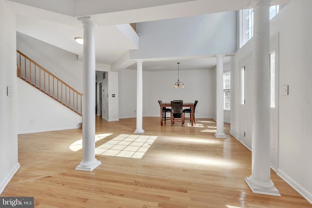 unfurnished dining area featuring light hardwood / wood-style floors, a high ceiling, and an inviting chandelier