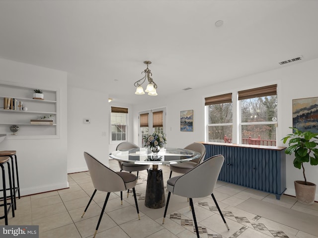 dining room with built in features, light tile patterned floors, and a notable chandelier