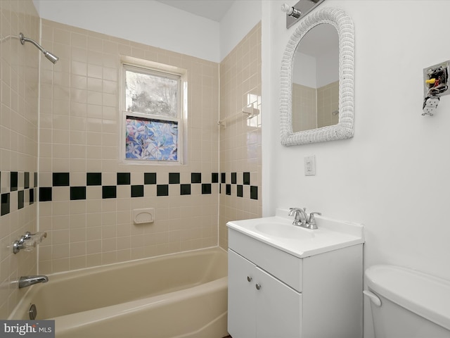 full bathroom featuring tiled shower / bath, vanity, and toilet