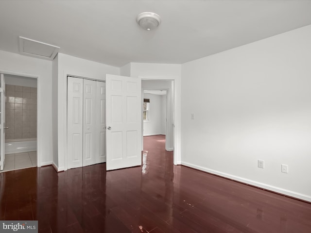 unfurnished bedroom with dark wood-type flooring and a closet