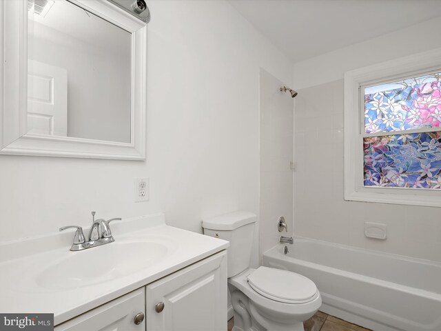 full bathroom featuring tiled shower / bath, vanity, and toilet