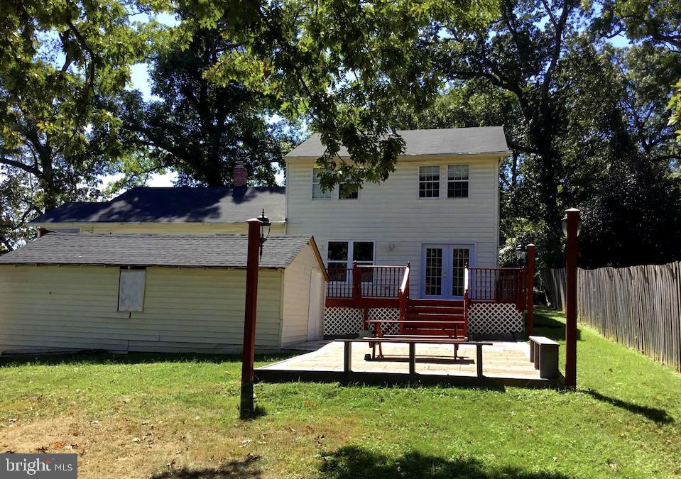 rear view of house featuring a lawn and a wooden deck