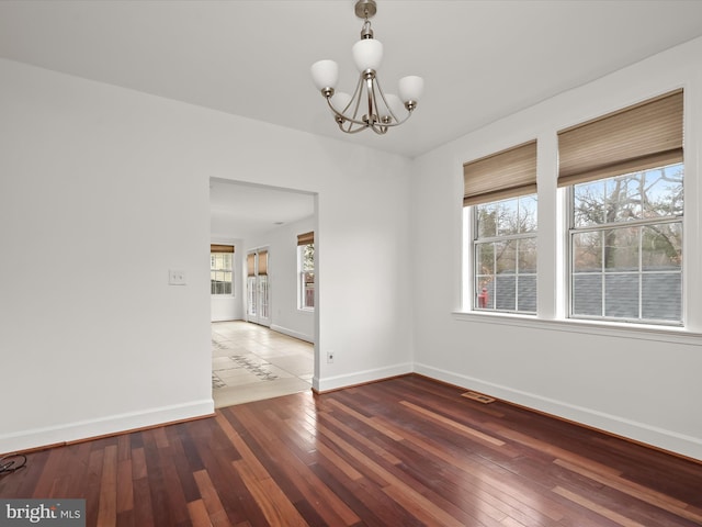 unfurnished room with hardwood / wood-style flooring, plenty of natural light, and an inviting chandelier