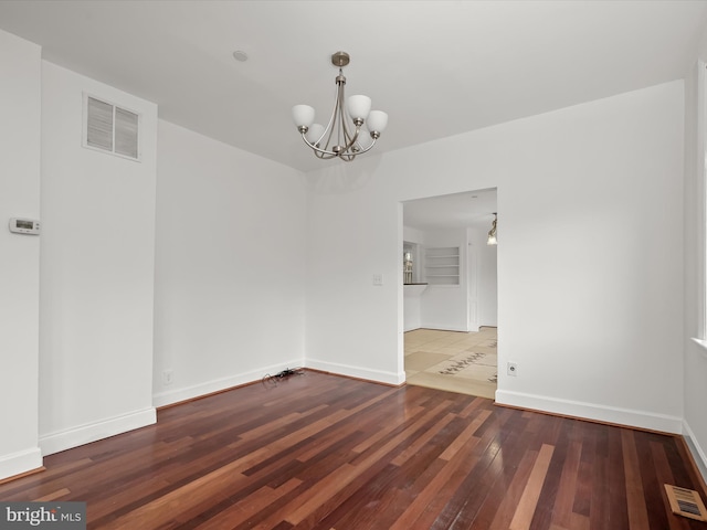 unfurnished room with an inviting chandelier and wood-type flooring