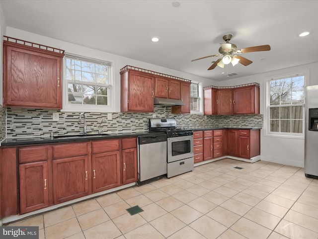 kitchen with light tile patterned flooring, appliances with stainless steel finishes, tasteful backsplash, sink, and ceiling fan