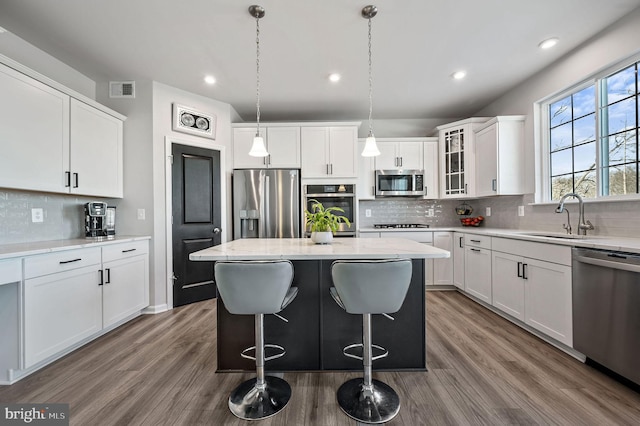 kitchen featuring sink, white cabinetry, a kitchen island, stainless steel appliances, and light stone countertops