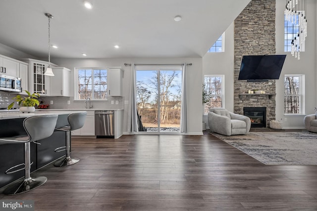 living room featuring dark wood-type flooring, high vaulted ceiling, a fireplace, and sink