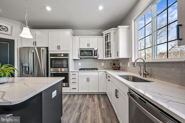 kitchen with appliances with stainless steel finishes, decorative light fixtures, sink, and white cabinets