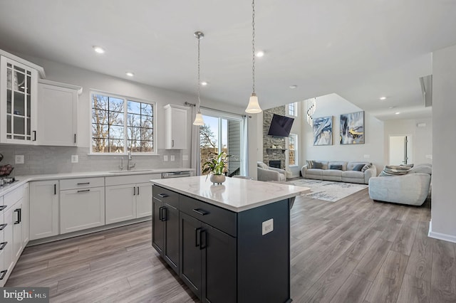 kitchen with pendant lighting, light hardwood / wood-style flooring, white cabinets, and a kitchen island