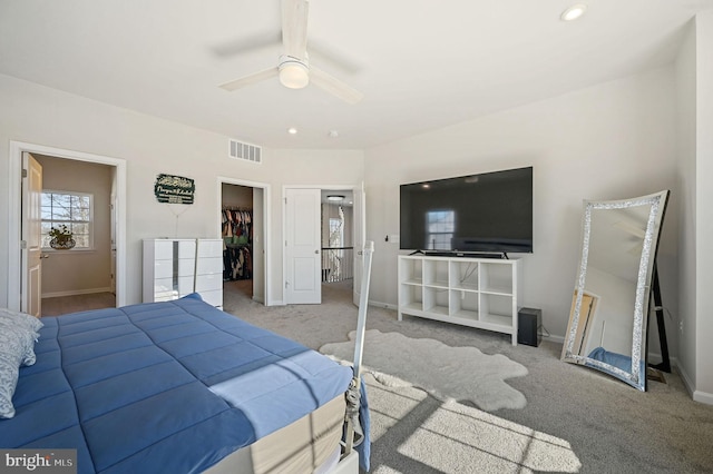 bedroom with ensuite bath, ceiling fan, a walk in closet, light colored carpet, and a closet