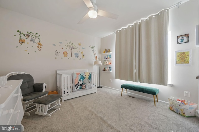 carpeted bedroom with a nursery area and ceiling fan