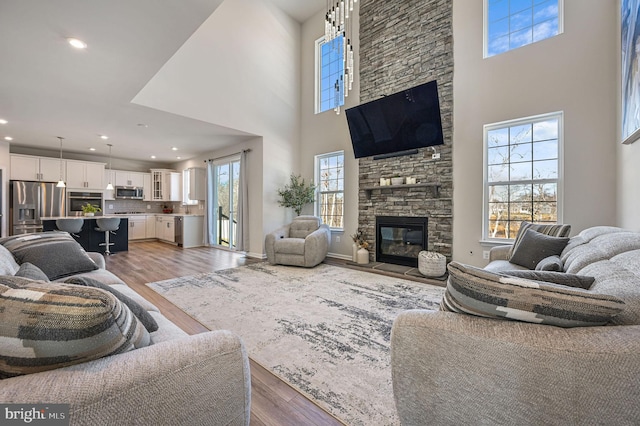 living room featuring dark hardwood / wood-style floors, plenty of natural light, a fireplace, and a high ceiling